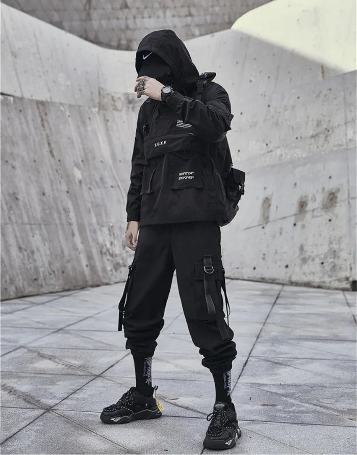 Person wearing a black outfit with a hood in an urban setting