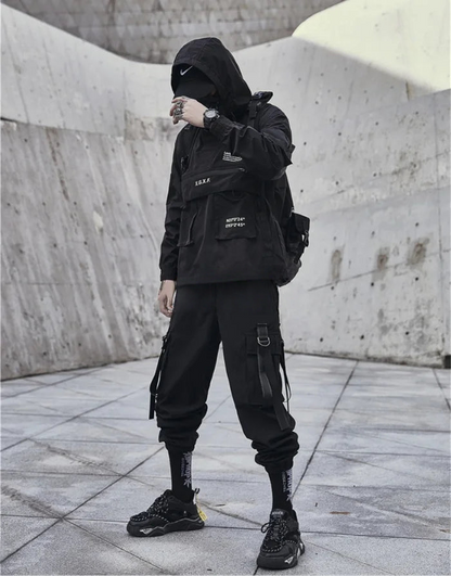 Person wearing a black outfit with a hood in an urban setting