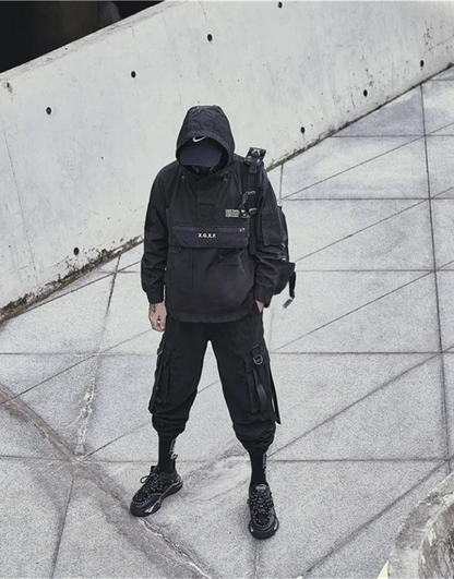 Person wearing a black outfit with a backpack against a concrete wall.